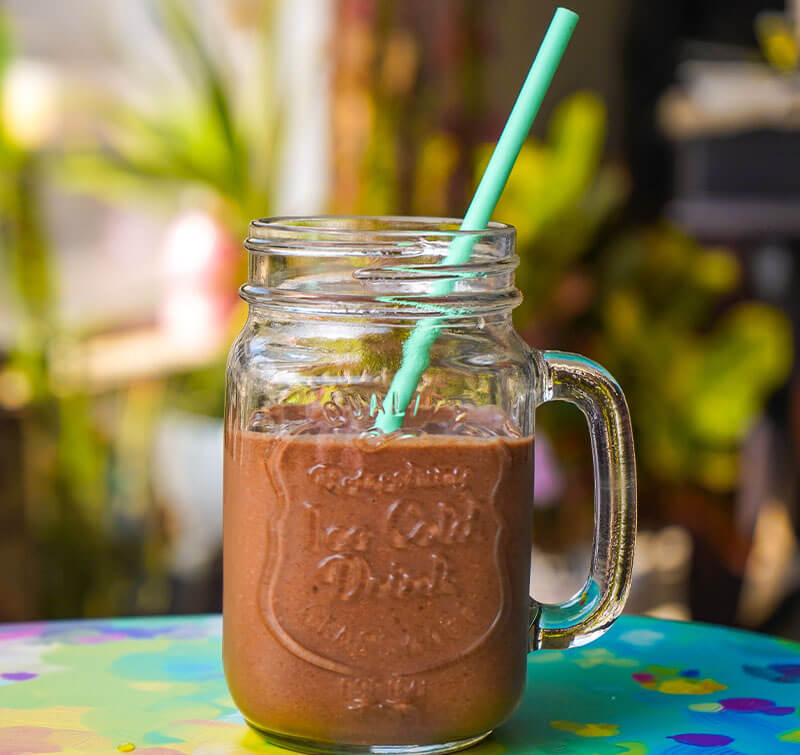 A glass of sugar-free chocolate maca smoothie on a table prepared by Dr. Cherine