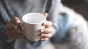 Hand holding a cup of warm water, a natural way to aid in energy conservation and vitality