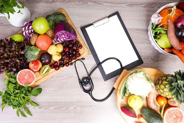 Notebook surrounded by fruits and vegetables for Dr. Cherine's nutrition program for clients.